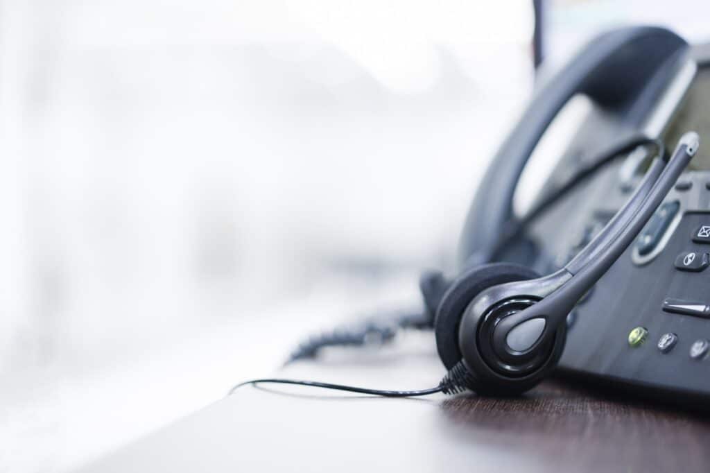 close up on headset devices of call center career with telephone (voip) on table of helpdesk agency