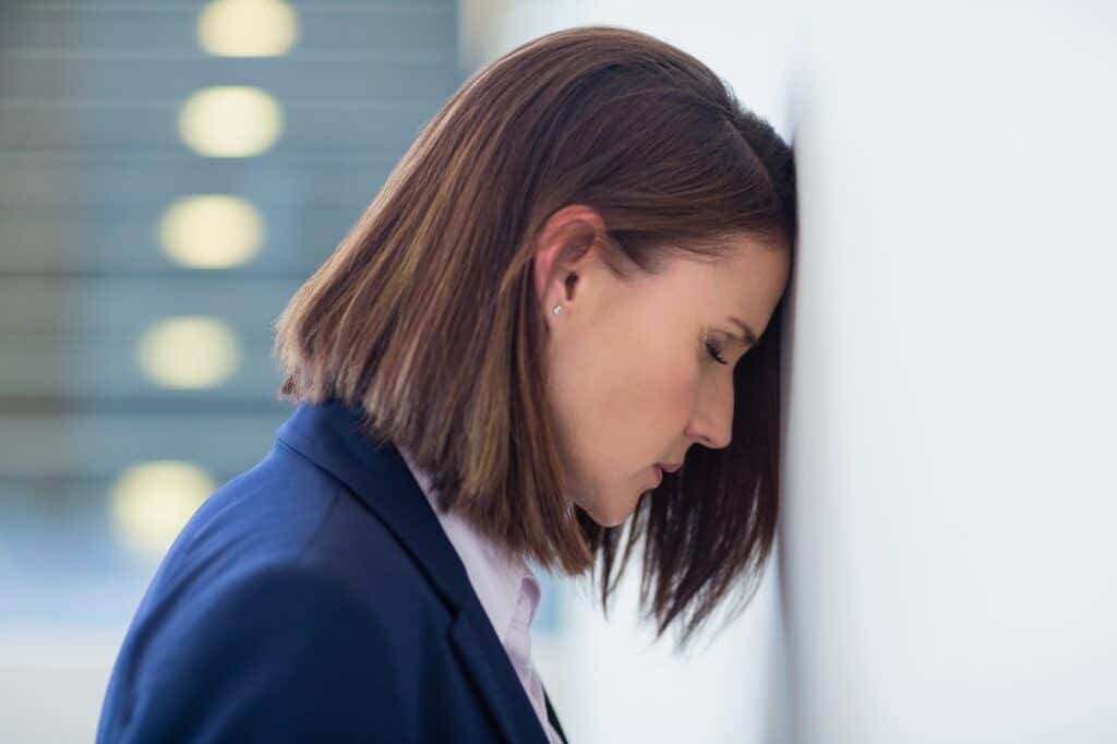 Worried businesswoman leaning her head on wall
